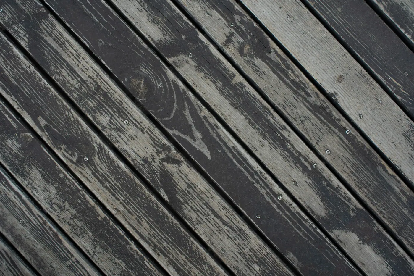 Before: weathered grey deck boards with worn, peeling stain
