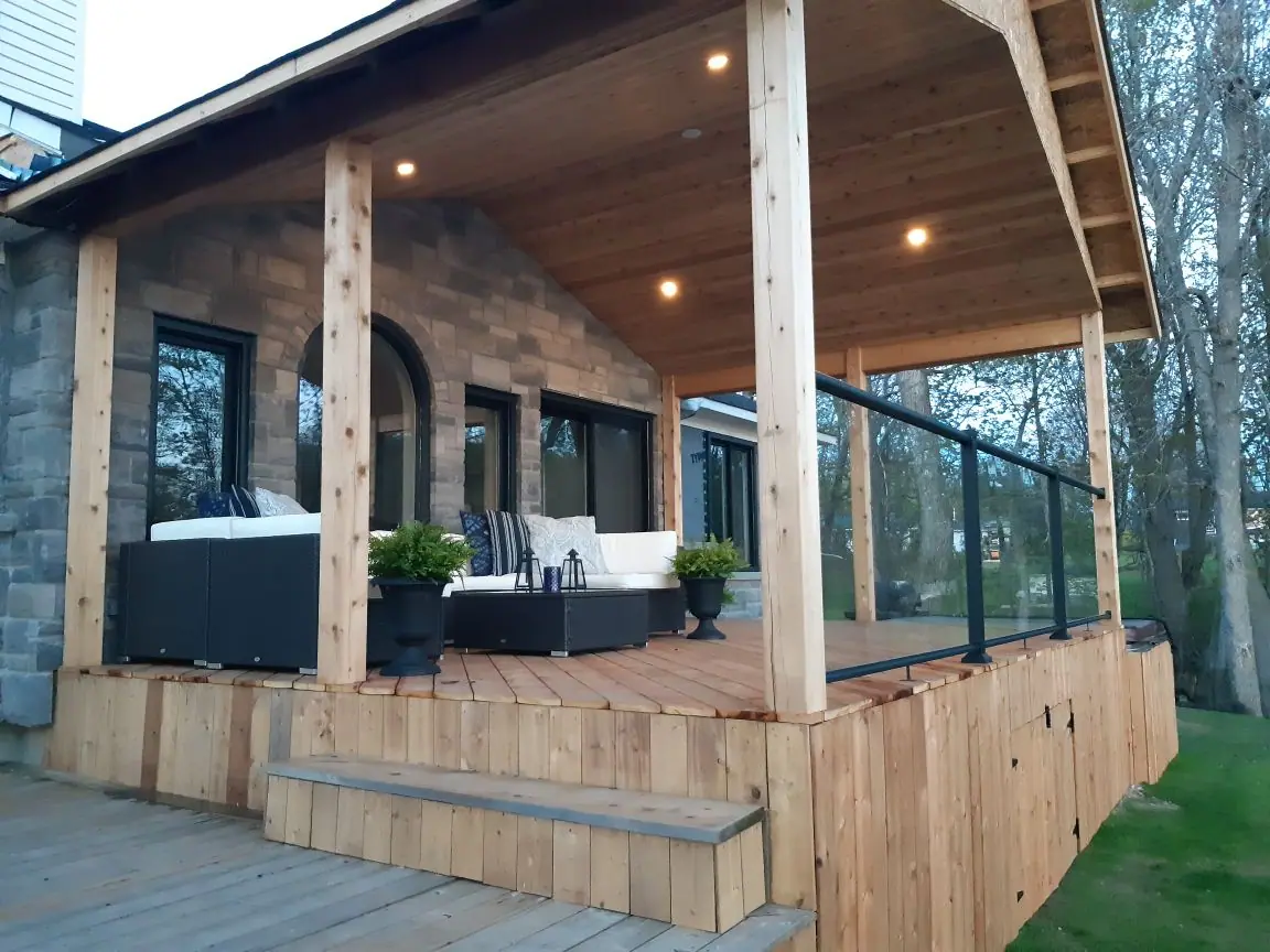 Covered cedar deck with black-framed glass railing and pot lights