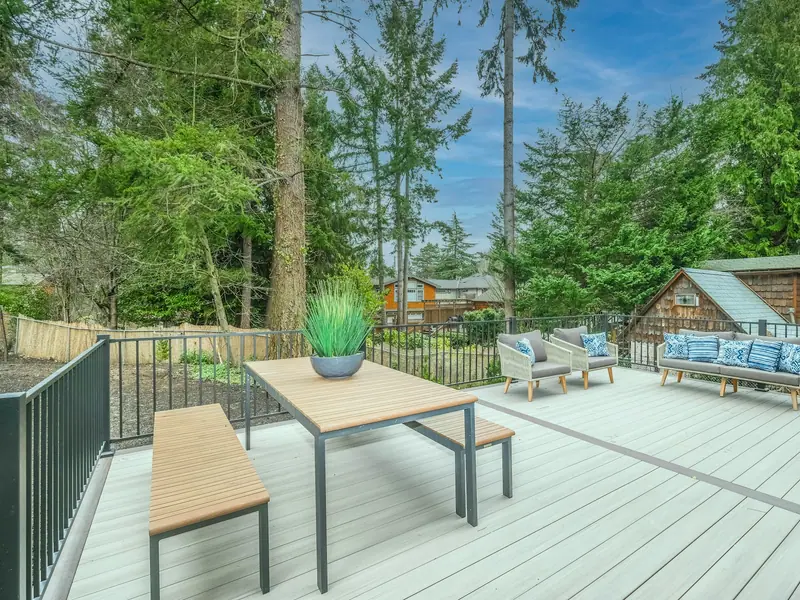 Grey composite deck with black aluminum railing, outdoor dining table and lounge chairs